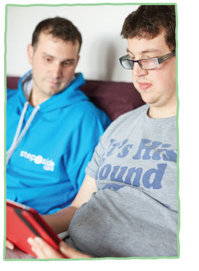 Adult care client looking at iPad with Care staff member